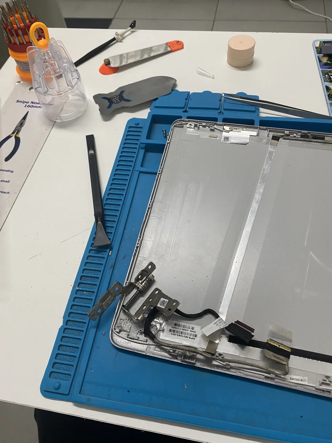 Laptop hinge and display cable being repaired on the workbench